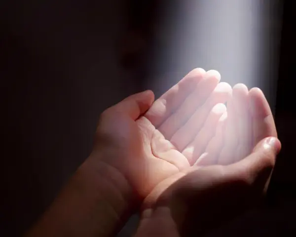 Hände im Licht, die Hoffnung suchen. Ein Symbol für gott und das Leid, das durch Glauben überwunden werden kann.