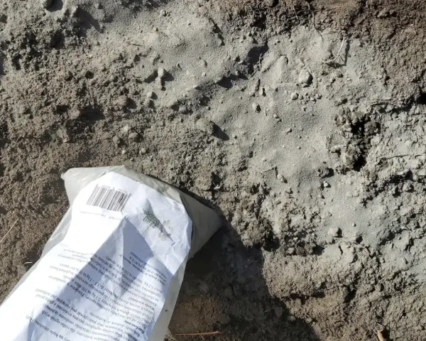 Opakowanie mączki bazaltowej leży na ziemi, gotowe do zastosowania w ogrodzie.
