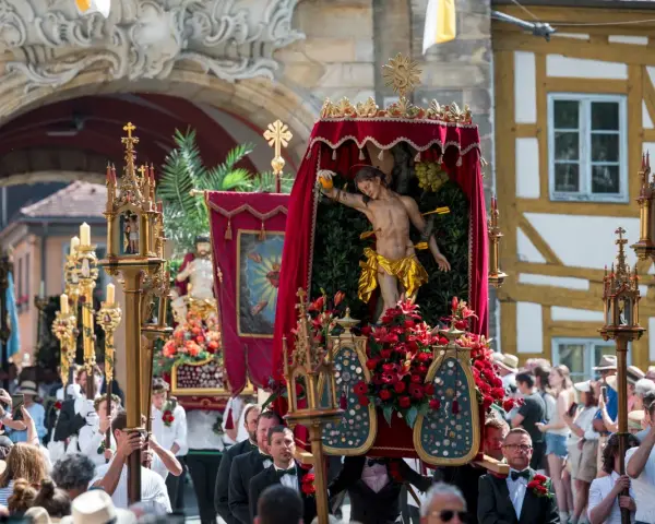 Prozession mit Jesus-Figur und Blumen. Fronleichnam ist ein gesetzlicher Feiertag, an dem solche Umzüge stattfinden.