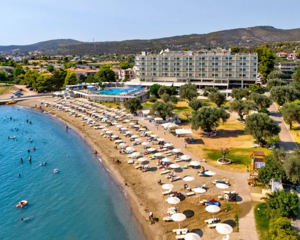 Piękna plaża na Evii, idealna na wycieczki fakultatywne. Hotel, basen, leżaki i mnóstwo ludzi kąpiących się w morzu.