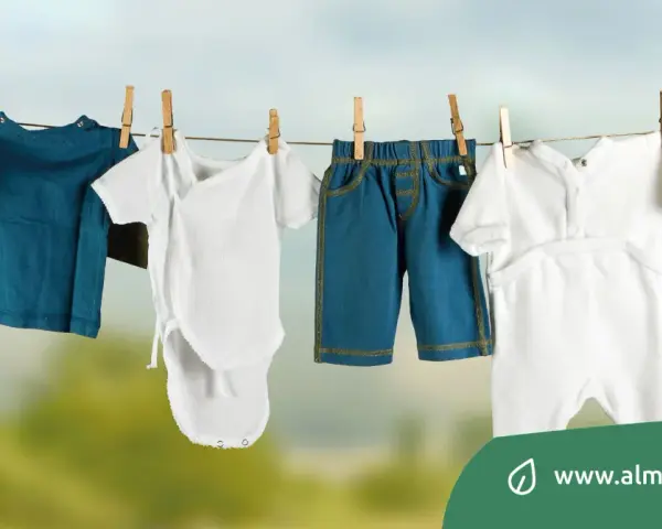 Baby clothes hanging on a clothesline: a blue long-sleeve shirt, a white onesie, blue shorts, and a white romper.