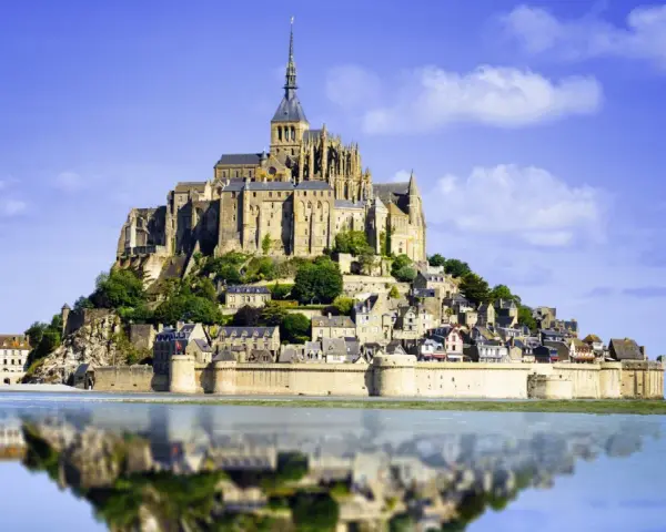 Opactwo Mont Saint-Michel, jeden z najpiękniejszych miejsc we Francji, odbija się w spokojnej wodzie.