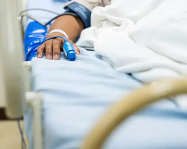 Paciente en cama de hospital con oxímetro en el dedo, indicando la necesidad de permiso por enfermedad.