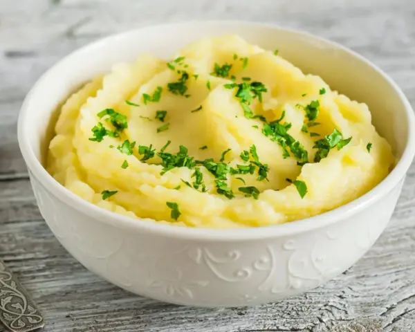 Puszyste, kremowe puree ziemniaczane, posypane świeżą natką pietruszki. Idealny dodatek do obiadu, który pokazuje, jak zrobić puree.