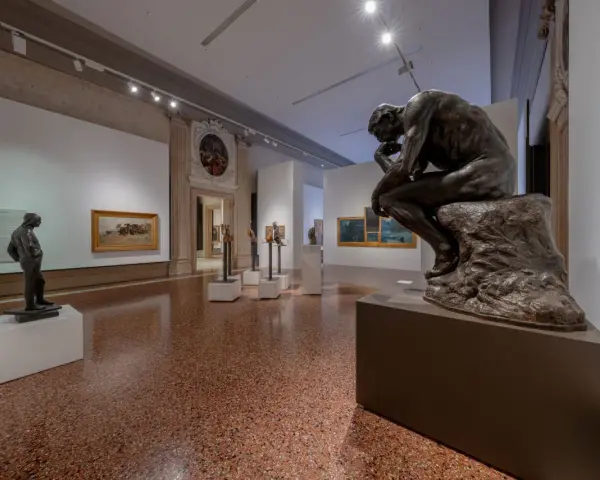 Il Pensatore di Rodin in una sala espositiva, forse a Venezia ca Pesaro, riflette sul significato dell'arte.