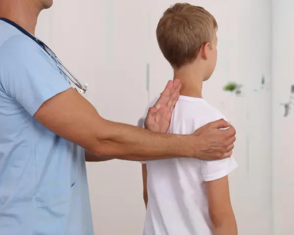 Lekarz bada chłopca, sprawdzając jego postawę. Może to być część diagnostyki zespołu Marfana objawy.