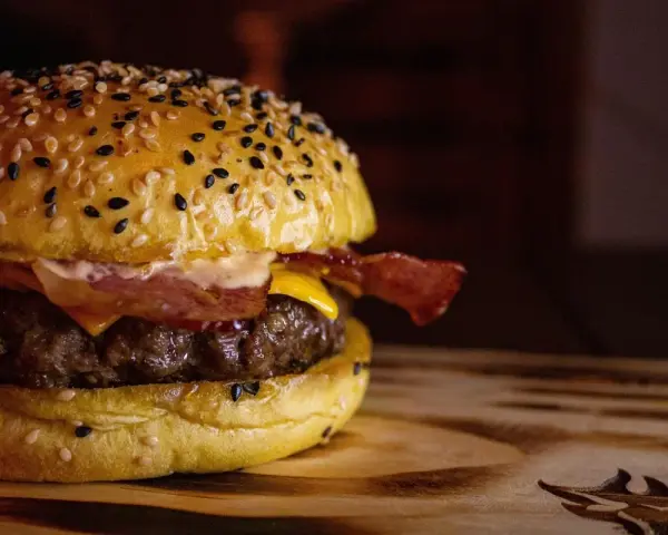 Soczysty burger z bekonem i serem na bułce z sezamem.