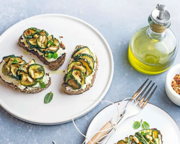 Bruschetta con zucchine grigliate, ricotta e pinoli, condita con un filo d'olio.
