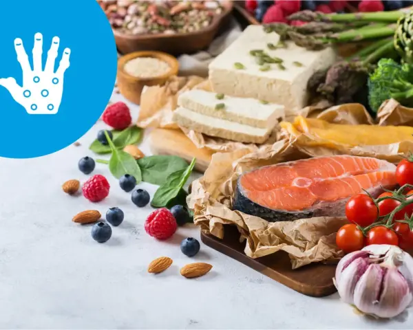 Zdrowa dieta przy łuszczycy: łosoś, warzywa, owoce, orzechy i tofu. Ikona dłoni symbolizuje ulgę.