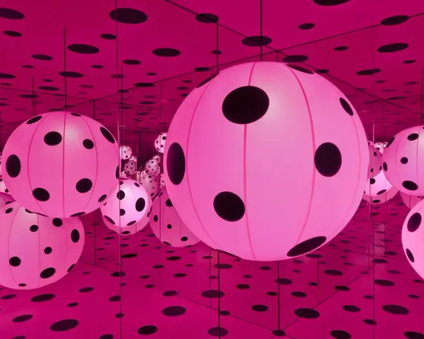 Salle infinie de Yayoi Kusama, remplie de sphères roses lumineuses à pois noirs, reflétées à l'infini par des miroirs.