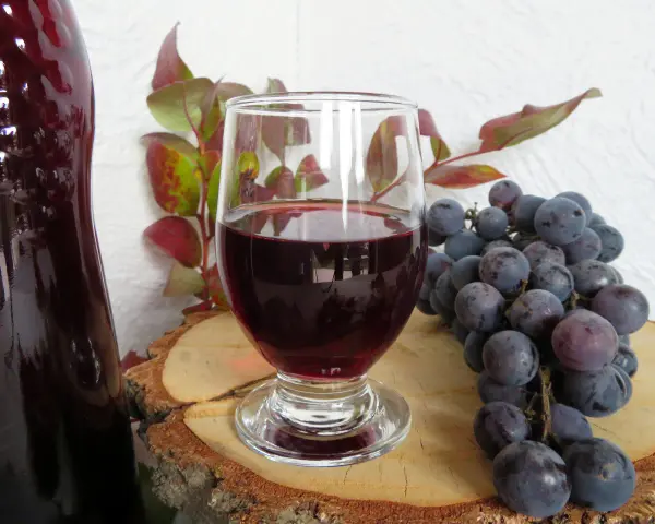 Wino z ciemnych winogron, kieliszek, kiść winogron i butelka. Idealne na przepis na wino z ciemnych winogron.