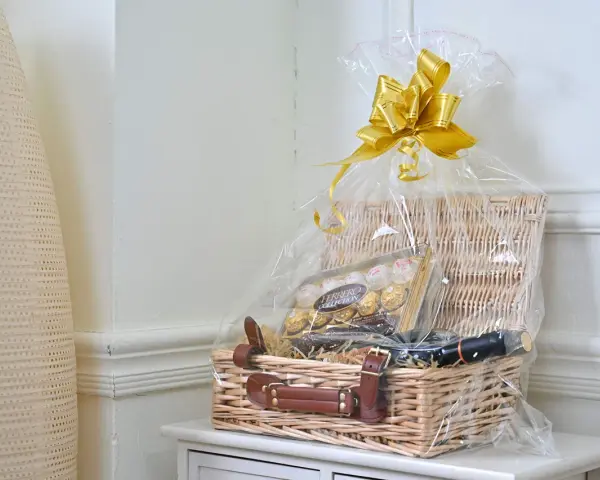 En vacker presentkorg med Ferrero Rocher-choklad och en flaska vin, inslagen i cellofan med en gyllene rosett.