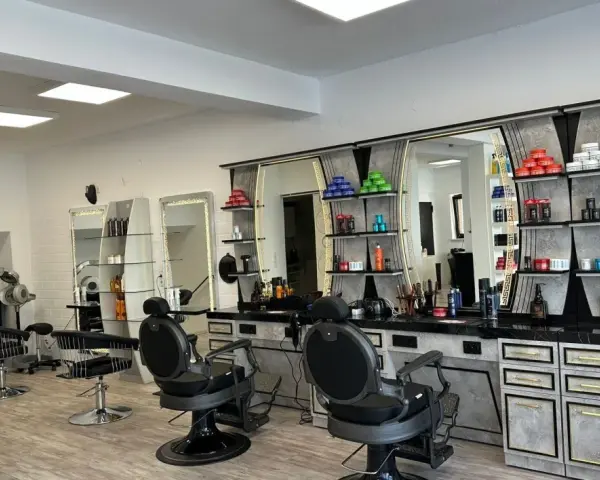 Friseurstuhl und Spiegel in einem modernen Salon mit Regalen voller Kosmetikprodukte.