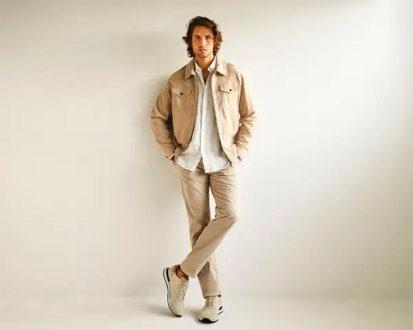 Hombre con ropa business casual en tonos beige: chaqueta, camisa y pantalones.