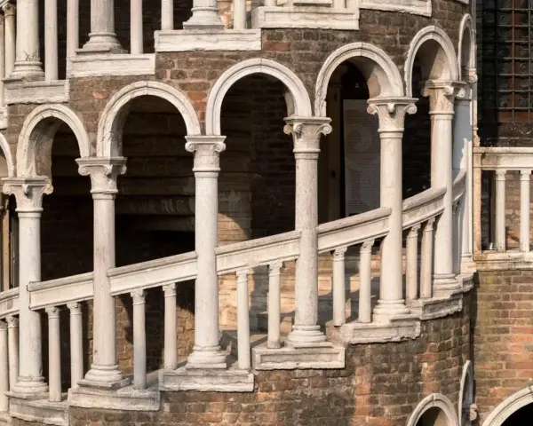 La scala Contarini a Venezia, con i suoi archi e colonne in marmo bianco, si snoda su una struttura in mattoni rossi, un'elegante spirale nel tempo.