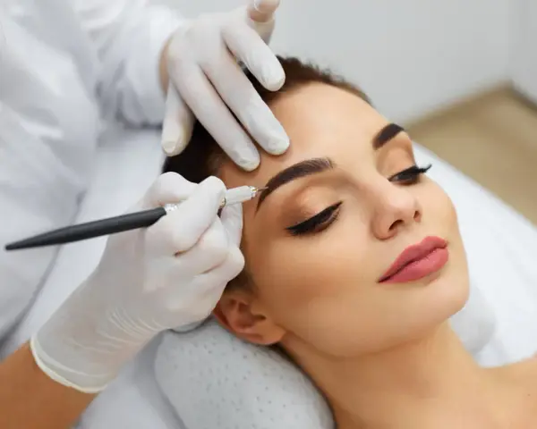 Une esthéticienne crée des sourcils brossés vers le haut sur une cliente, perfectionnant son regard avec précision.
