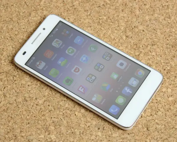 Biały smartfon Huawei G620S leżący na korkowym tle, z widocznym ekranem głównym.