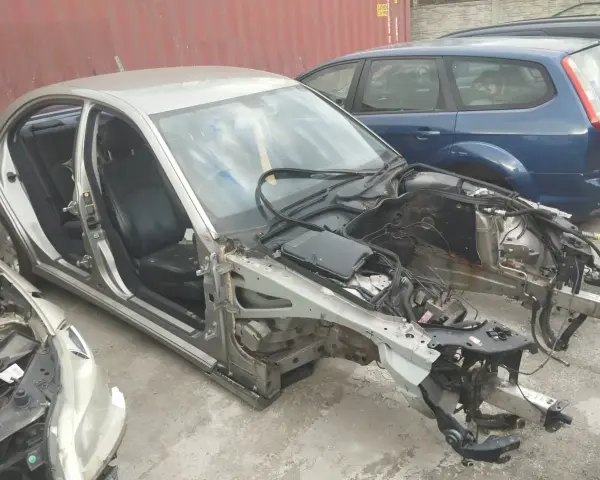 Złomowanie auta: srebrny sedan bez maski i zdemontowanymi częściami, obok niebieski kombi.
