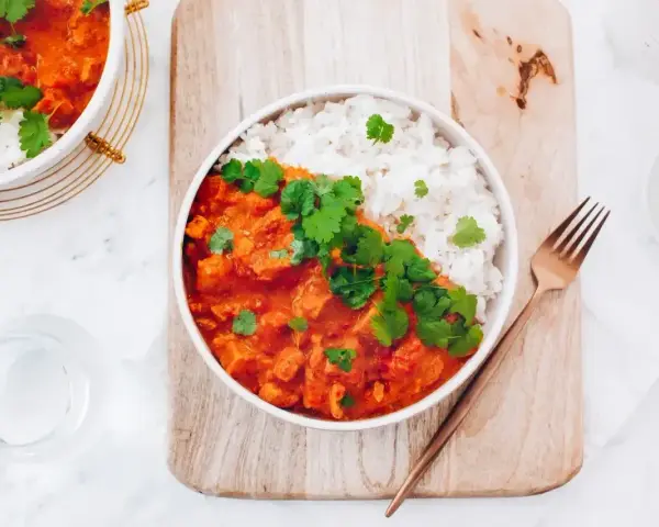 Pyszne czerwone curry z kurczakiem i ryżem, udekorowane świeżą kolendrą. Idealny przepis na obiad.