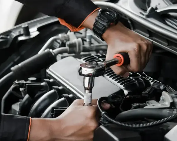Mechanik wykonuje wymiana pompy paliwa krok po kroku, używając klucza nasadowego do odkręcenia śrub w silniku samochodu.