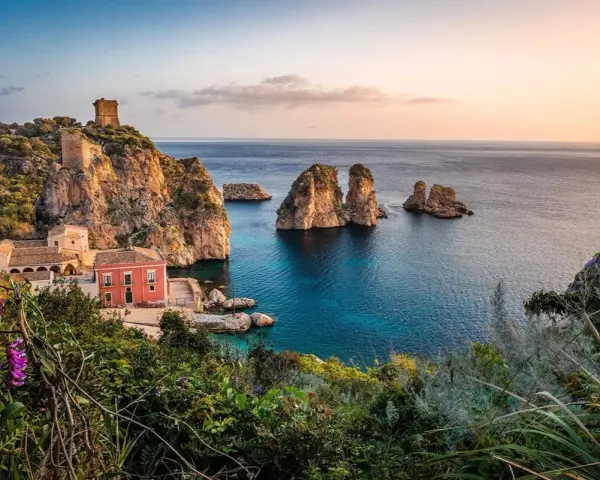 Traumhafte Küstenlandschaft mit Felseninseln, einem alten Turm und einem roten Haus. Perfekt für ein Auslandsjahr in Italien.