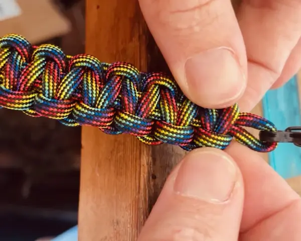 Mani che chiudono un braccialetto colorato con filo, mostrando come chiudere un braccialetto con filo.
