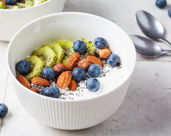 Schüssel mit Magerquark, Blaubeeren, Kiwi, Mandeln und Chiasamen. Perfekt für gesunde Magerquark Rezepte.