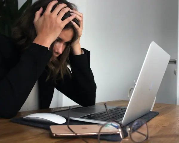 Femme stressée devant son ordinateur, les mains sur la tête, face à une saisie administrative à tiers détenteur.