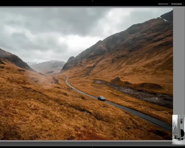 Paysage écossais traité dans Lightroom, avec une voiture sur une route sinueuse. L'ouverture sur la lumière de Lightroom France révèle des teintes chaudes et dramatiques.