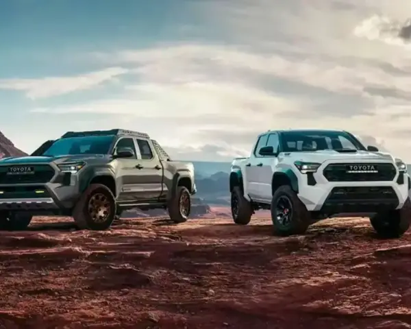Dwa nowe modele toyota pickup, biały i szary, gotowe na przygodę w surowym, pustynnym krajobrazie.