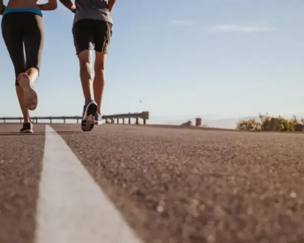 Coppia corre su strada asfaltata, godendosi la libertà e la velocità media corsa sotto un cielo azzurro.