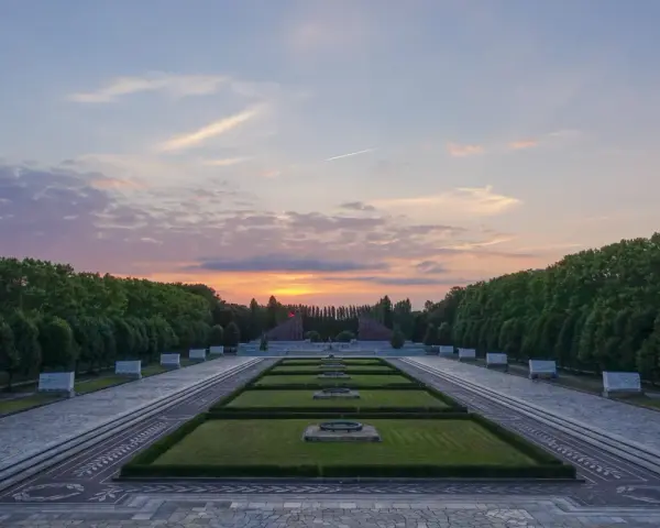 Sonnenuntergang über dem Sowjetischen Ehrenmal in Berlin. Ein beeindruckendes Beispiel für Parks in Berlin, mit symmetrischen Rasenflächen und einer langen Allee.