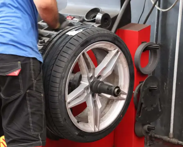 Meccanico effettua la bilanciatura gomme su un'auto sportiva. L'operazione garantisce una guida fluida e sicura.
