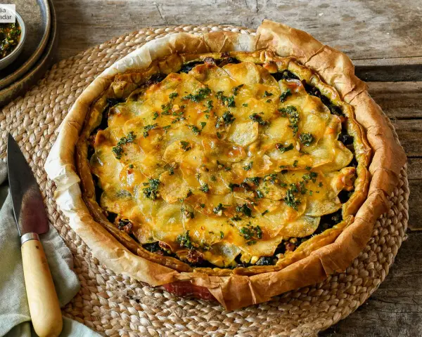 Delicioso quiche de espinacas con patatas laminadas y hierbas frescas, listo para servir.
