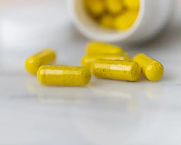 Capsule gialle sparse su una superficie chiara. La berberina a cosa serve? Potrebbe essere la risposta in queste capsule.
