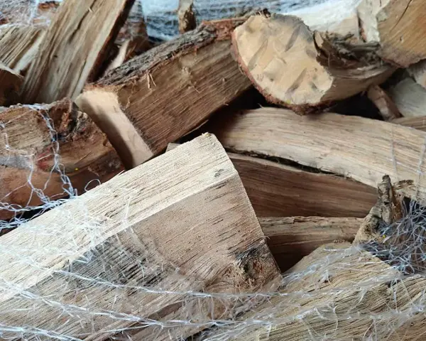 Gros plan sur un poids stère de bois sec, emballé dans un filet blanc, prêt pour l'hiver.