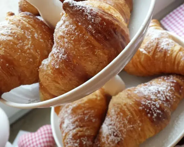 Cornetti fatti in casa, dorati e spolverati di zucchero a velo, invitano a una colazione golosa.