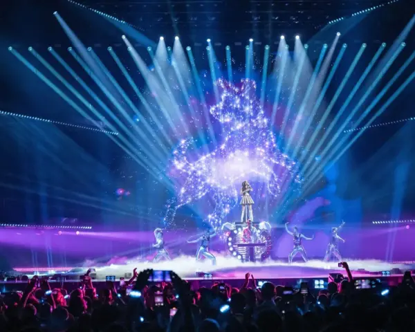 Wokalistka na scenie Eurowizji, otoczona tancerzami i efektami świetlnymi. Widownia filmuje występ, zastanawiając się, ile krajów w finale Eurowizji.