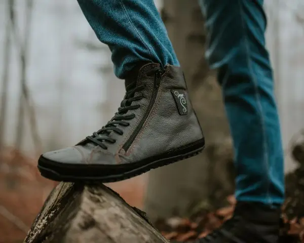 Szare buty barefooty na drewnianym pniu, w jesiennym lesie.