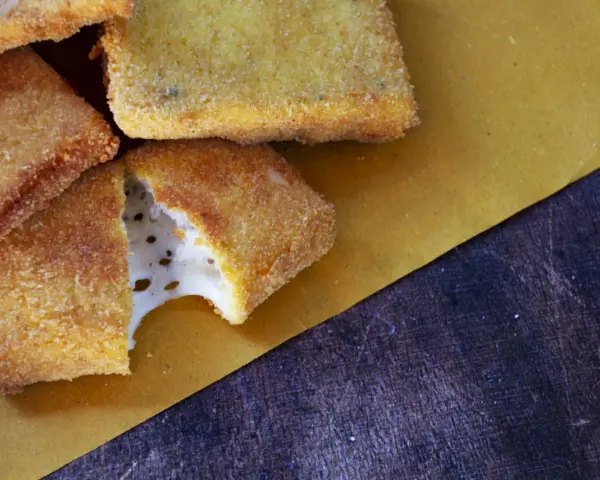 Mozzarella in carrozza dorata e croccante, con il formaggio filante che fuoriesce da uno dei pezzi.