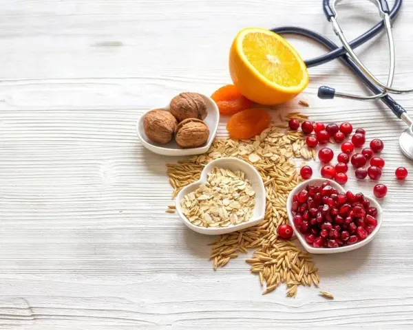 Sposób babci na obniżenie cholesterolu: orzechy, owsianka, żurawina, granat, pomarańcza i suszone morele. Stetoskop symbolizuje zdrowie.