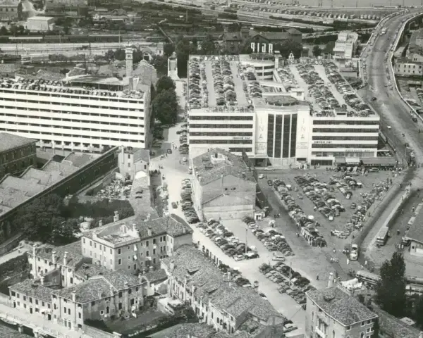Vista aerea del parcheggio San Andrea a Venezia, con file di auto parcheggiate su più livelli e un edificio INA.