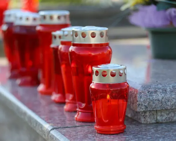 Rote Grablichter brennen auf einem Grabstein. Am 1. November, dem Feiertag Allerheiligen, werden sie zum Gedenken entzündet.