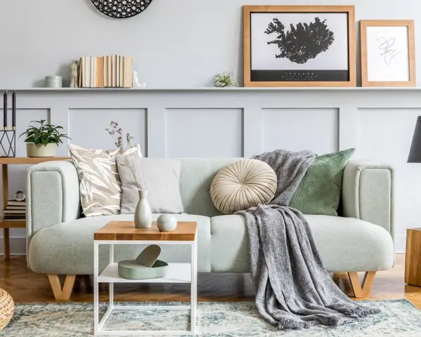 Un plaid gris drapé sur un canapé vert menthe, ajoutant une touche cosy. Idée pour comment mettre un plaid sur un canapé.