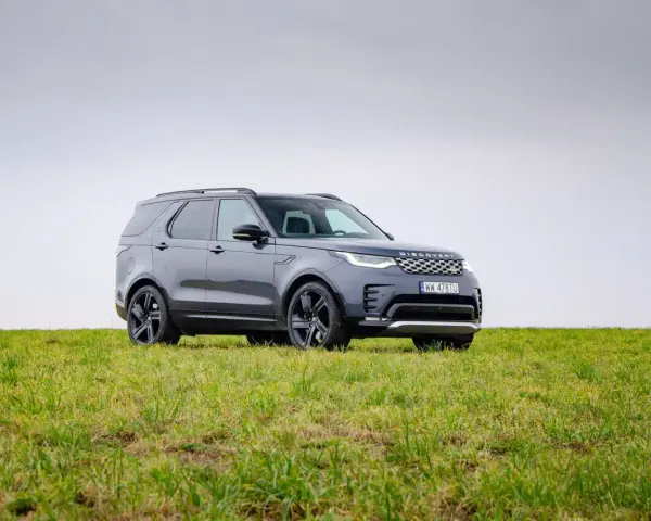 Szary Land Rover Discovery stoi na zielonej łące.