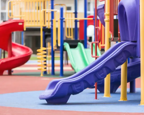 Aire de jeux colorée avec toboggans rouge, vert et violet.