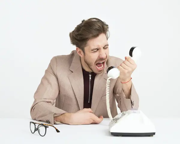 Mężczyzna w garniturze krzyczy do telefonu, jego twarz wyraża złość. Widać, że jest cholerykiem.