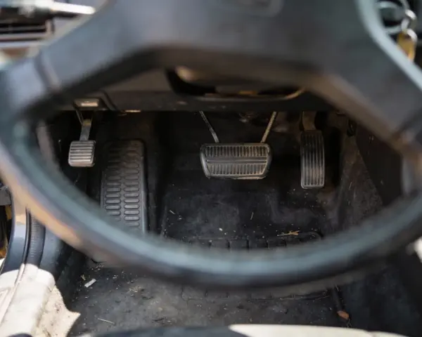 Widok na pedały samochodu. Sprzęgło, hamulec i gaz. Uważaj na jazdę na półsprzęgle, bo to męczy auto.