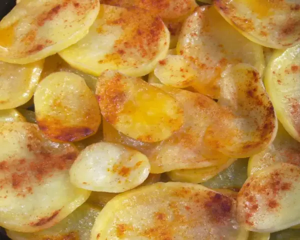 Rodajas de patatas fritas al horno, doradas y espolvoreadas con pimentón.