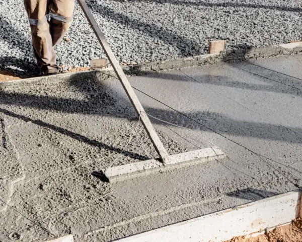 Un ouvrier lisse le béton frais pour créer une pente de terrasse.